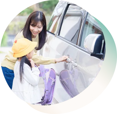 女性が子供を車に乗せるためにドアを開けようとしている様子